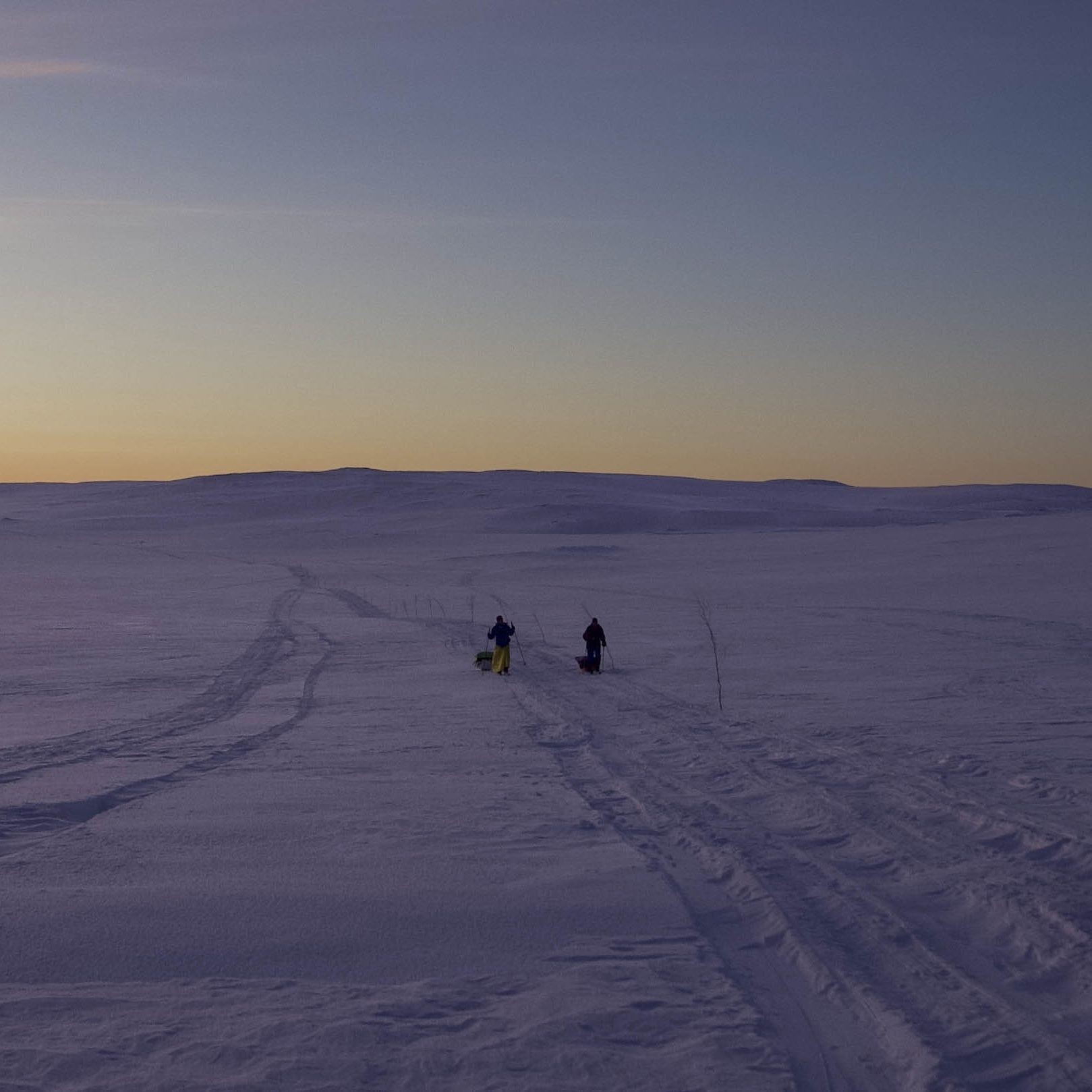 People walking in the snow at sunset