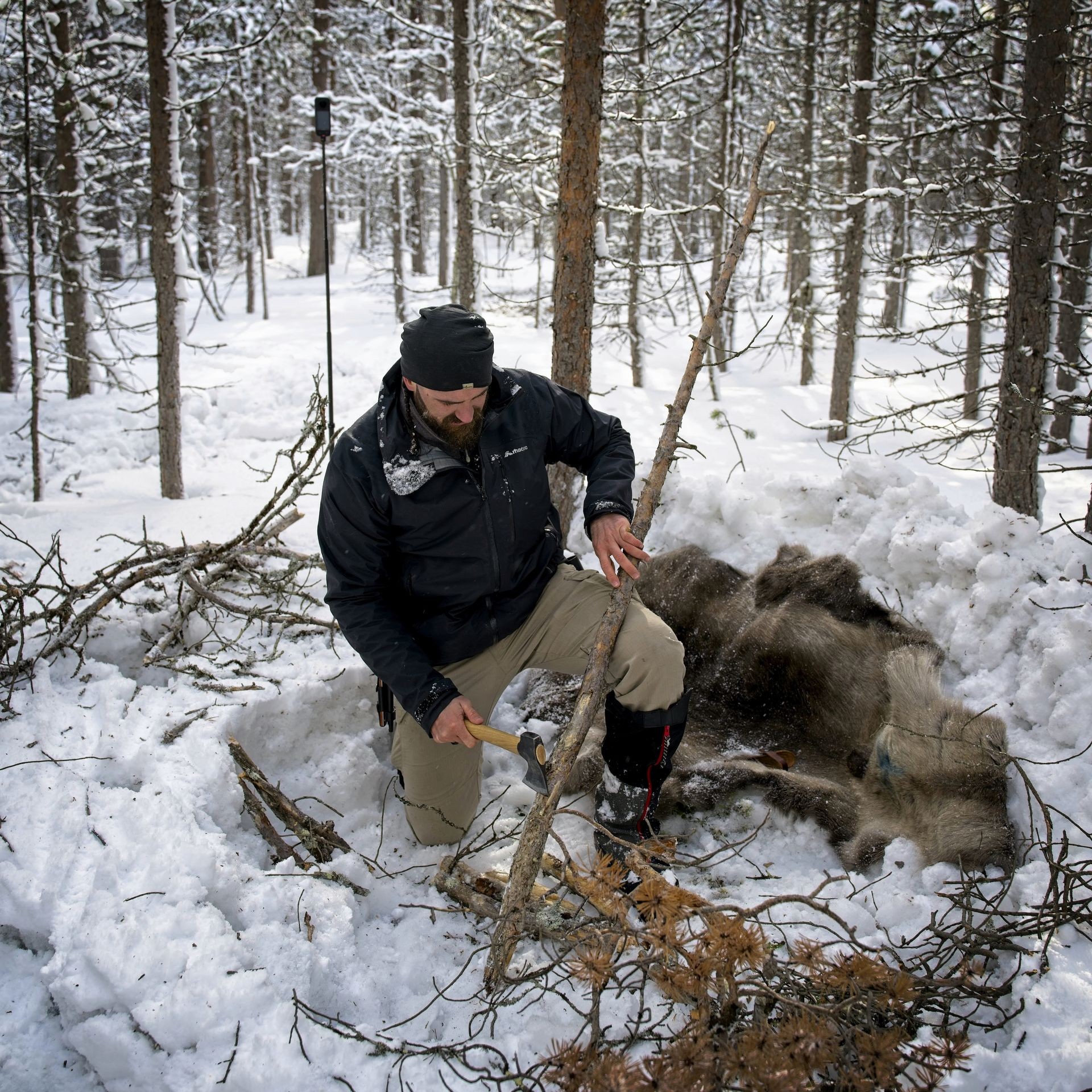 Man cutting wood with an axe for a fire in the snow